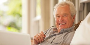 Portrait of smiling senior man using laptop on porch
